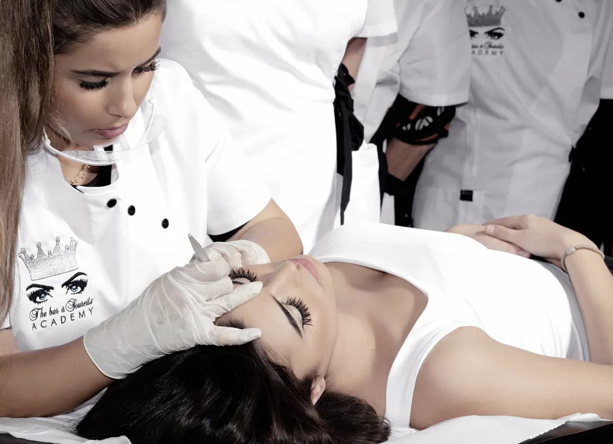 Praticienne travaillant les sourcils d'une cliente allongée